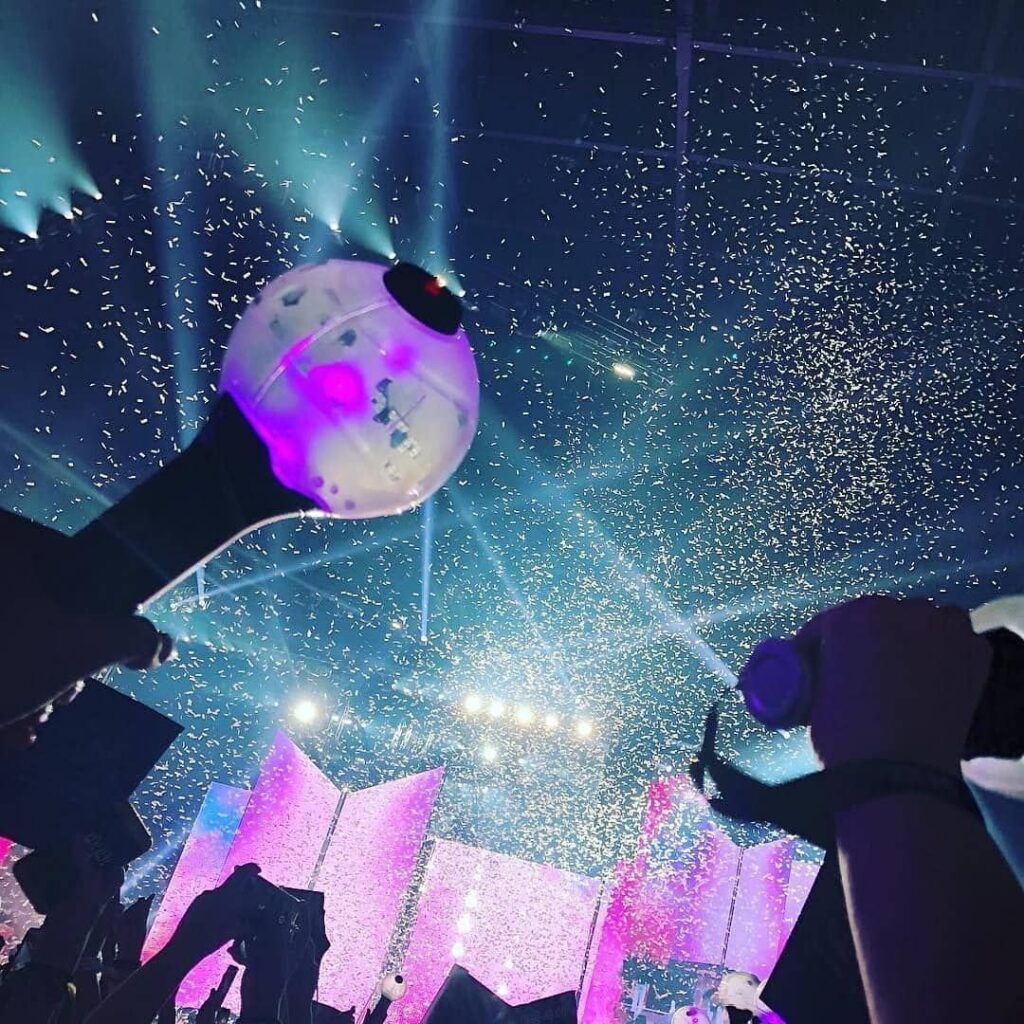 Fans holding K-Pop lightsticks during concert